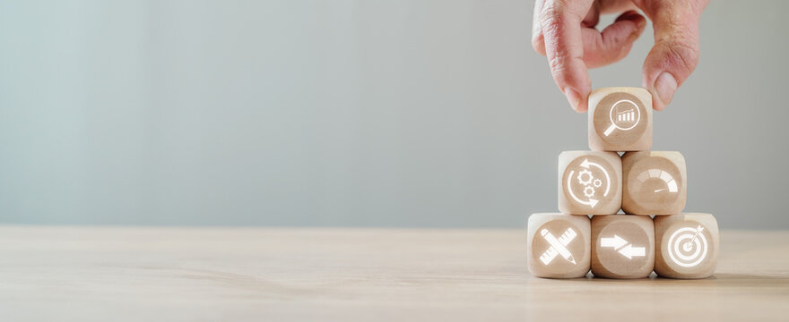 Benchmark concept, Hand holding wooden block on desk with performance, process, indicator, measurement, compare and target icon on virtual screen.