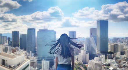 日本の街・都市・朝日を受けたオフィスビル群を前に佇み風を受けて髪をなびかせる会社員の女性の出勤　ビジネス・はじまり・決意・目標・挑戦のイメージ