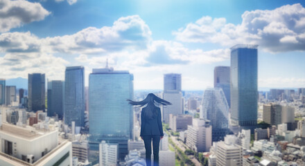 Obraz premium 日本の街・都市・朝日を受けたオフィスビル群を前に佇み風を受けて髪をなびかせる会社員の女性の出勤 ビジネス・はじまり・決意・目標・挑戦のイメージ