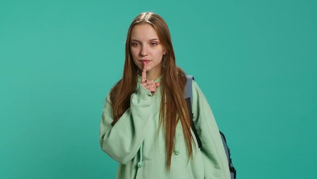 Stern woman doing shushing hand gesturing, irritated by noise, having negative mood. Girl placing finger on lips, doing quiet sign gesture, isolated over studio background, camera A