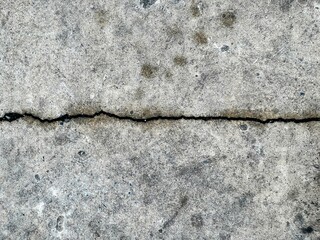 a photography of a crack in the concrete with a black line.