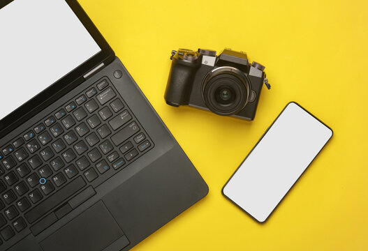Mockup of laptop and smartphone with white screens, camera on a yellow background. Top view. Flat lay. Modern gadgets - Powered by Adobe