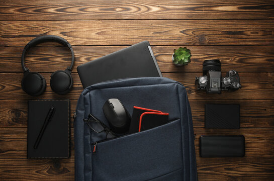 Backpack with photographer equipment and gadgets for work on a wooden background. Flat lay. Top view