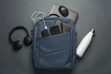 Laptop with Modern gadgets and accessories for work and study in Backpack on dark gray background....