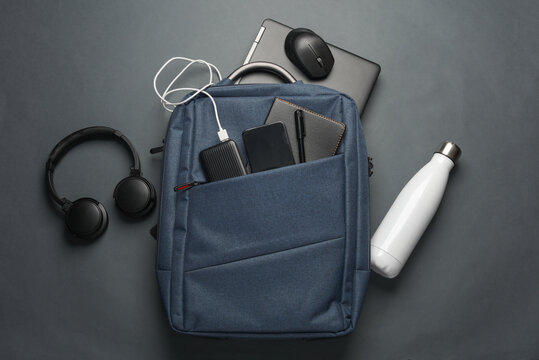 Laptop with Modern gadgets and accessories for work and study in Backpack on dark gray background. Top view. Flat lay