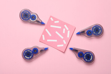 Tape corrector with memo paper on pink background. Top view