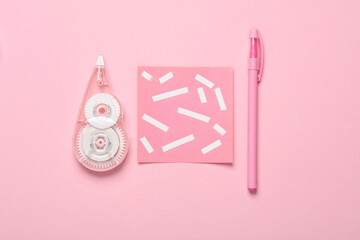 Tape corrector with memo paper and pen on pink background. Top view