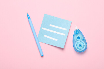 Tape corrector with memo paper and pen on pink background. Top view