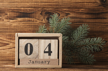 Wooden block calendar with date january 04 and pine tree on wooden background