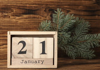 Wooden block calendar with date january 21 and pine tree on wooden background