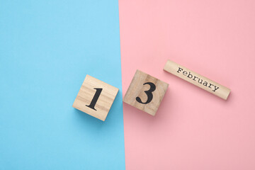 Wooden block calendar with date February 13 on pink blue pastel backround. Top view. Flat lay