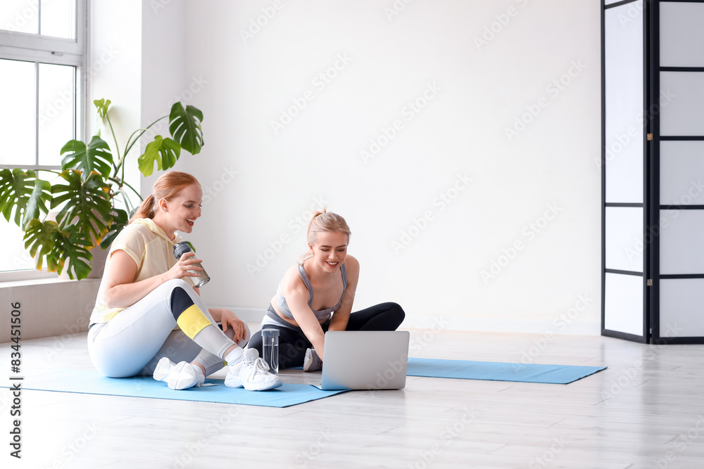 Poster Sporty young women with laptop in gym