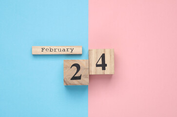 Wooden block calendar with date February 24 on pink blue pastel backround. Top view. Flat lay