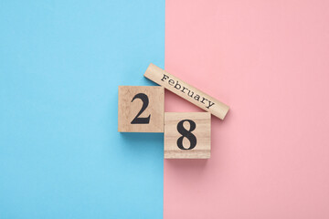 Wooden block calendar with date February 28 on pink blue pastel backround. Top view. Flat lay