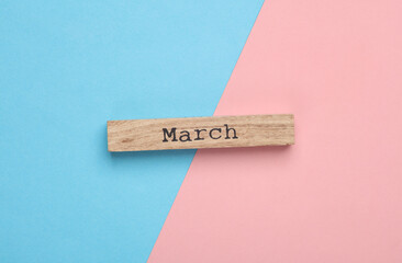 Wooden board with month March on blue pink background