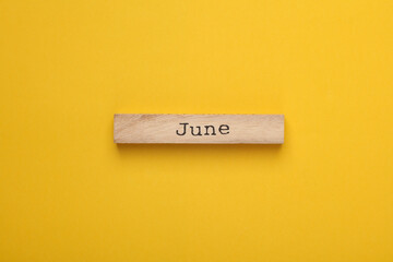 Wooden board with month June on yellow background