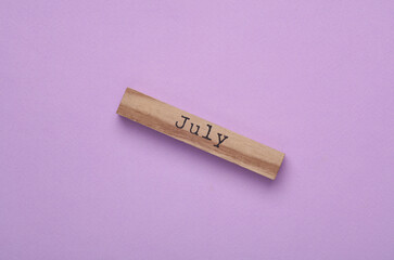 Wooden board with month Jule on purple background