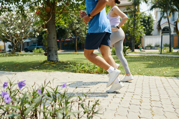 Man and woman running together in a park, focusing on their fitness routine in a sunny outdoor setting