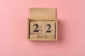 Wooden block calendar with date March 22 on pink  backround. Top view. Flat lay