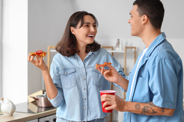 Young couple eating tasty pepperoni pizza in kitchen