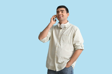 Happy young man talking by mobile phone on blue background