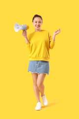 Young Asian woman with megaphone on yellow background