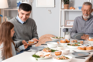 Little girl having dinner with her father at home on Hanukkah