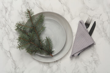 Plates, cutlery with towel, pine branch on marble background. Table setting