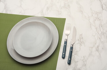 Plates and cutlery on marble background. Table setting. Top view