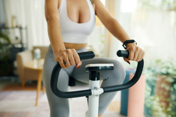 A detailed view of hands gripping the handlebars of an exercise bike, with the display panel in...