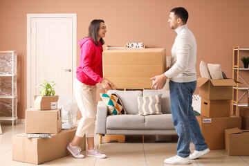 Happy young couple carrying box in room on moving day