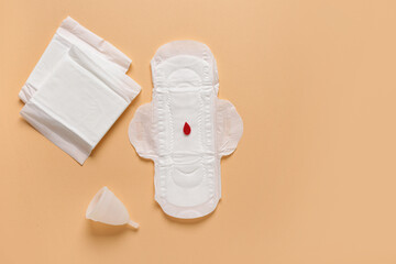 Menstrual pads with cup and paper blood drop on beige background