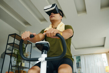 A man using a VR headset while exercising on a stationary bike in a modern living space with a...