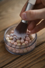 Hand holding makeup brush and Eye shadow balls on wooden background