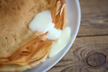 Pancakes with condensed milk on a wooden table