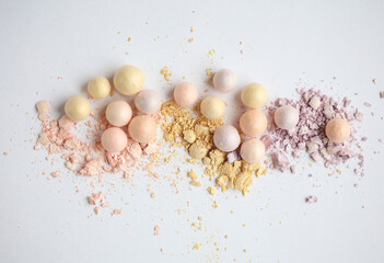 Crushed make-up balls of eye shadow on a white background close-up