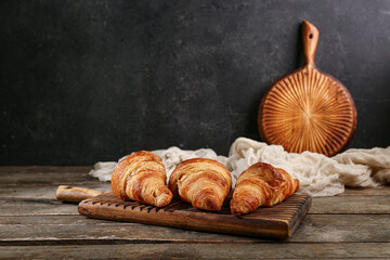 Board with tasty croissants on wooden table