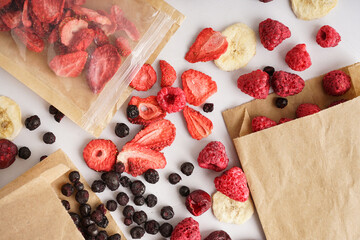 Craft bags with tasty freeze-dried fruits on white background