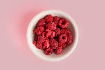 Bowl with freeze-dried raspberries on pink background
