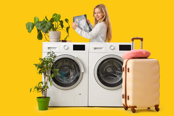 Girl with map, washing machines, plants in pots and suitcase on yellow background