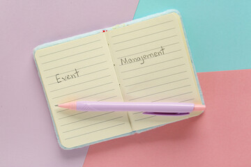 Open notebook with text EVENT MANAGEMENT and pen on colorful background. Time management concept. Top view