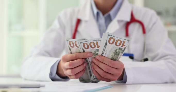 Doctor counts money at workplace in clini