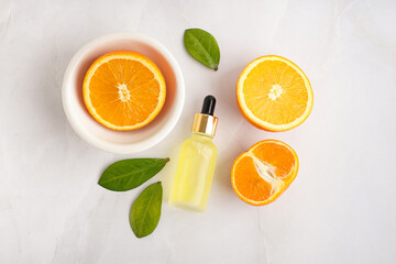Composition with bottle of essential oil and fresh orange on grey background