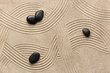 Black spa stones on light sand with pattern