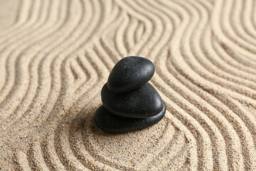 Fototapeta na wymiar Black stones on sand with lines. Zen concept