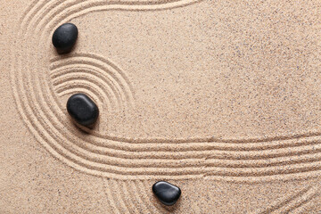 Black spa stones on sand background