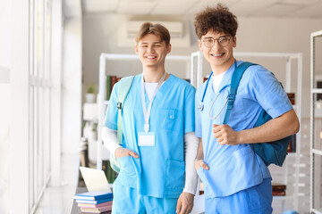 Male medical interns with backpacks near window in library