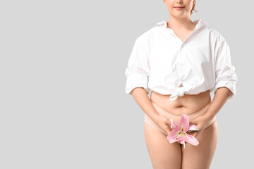 Young woman in period panties holding lily flower on white background
