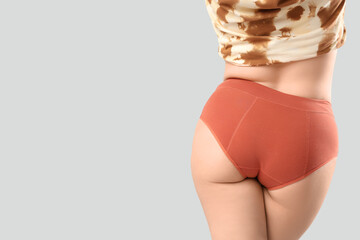 Young woman in menstrual panties on white background, back view