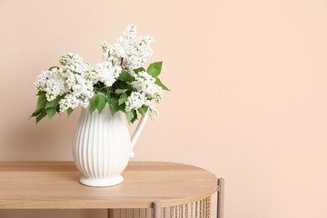 Vase with blossoming branches on coffee table near beige wall in room